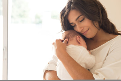 Pretty woman holding a newborn baby in her arms