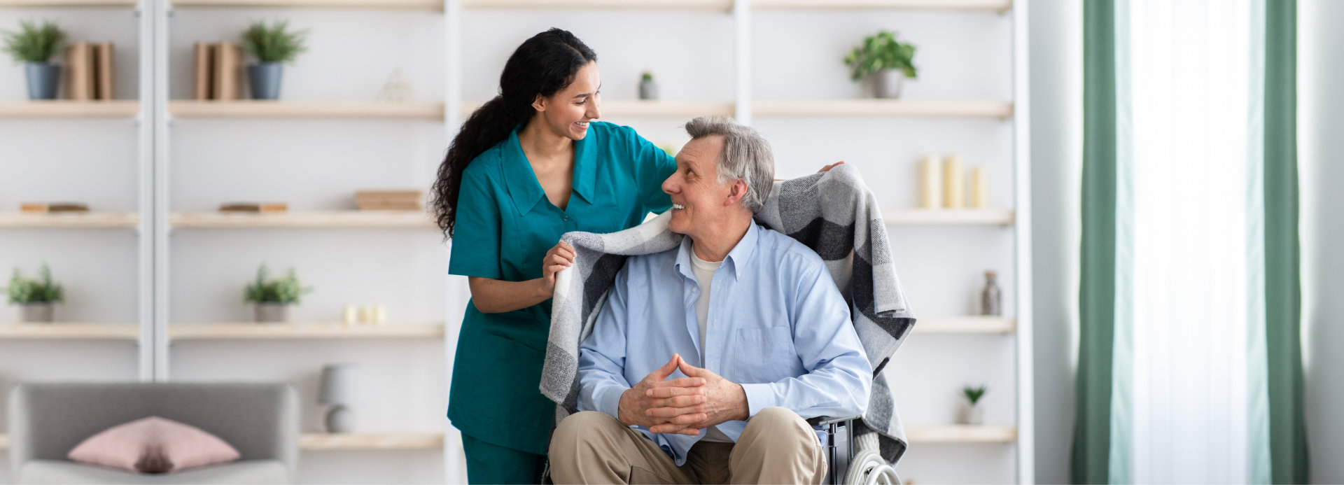 Senior man receiving assistance from caregiver indoors